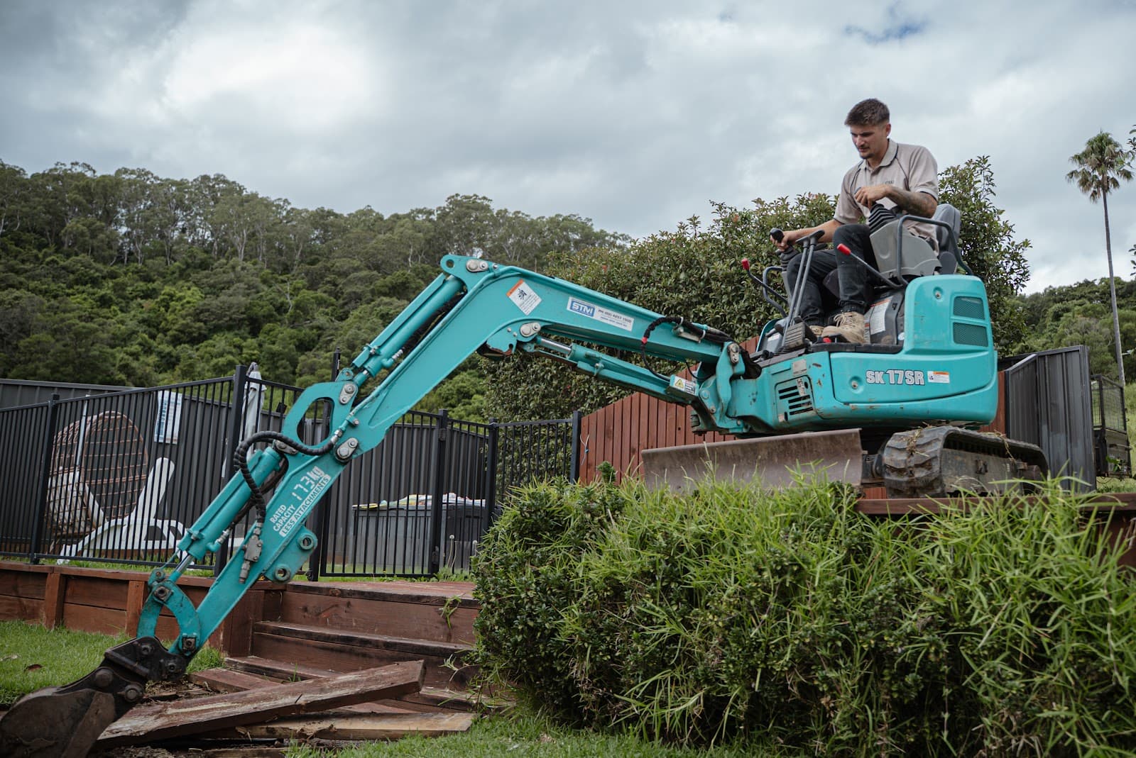 Excavator shaping a retaining batter on a sloped block